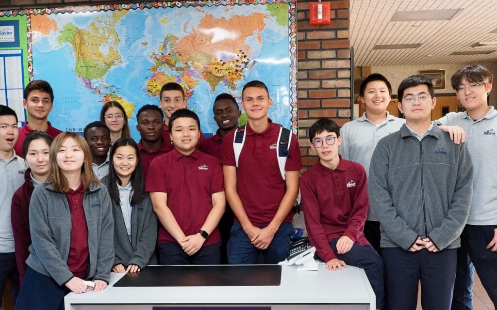 A group of students pose for a team photo in front of a map.