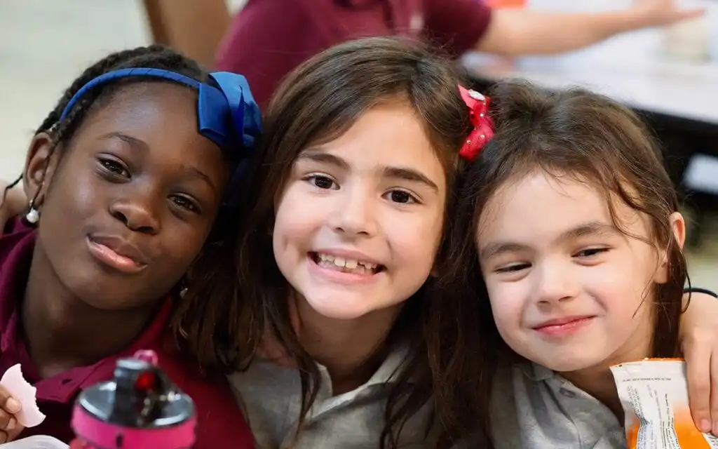 Three girls smile together for a photo.