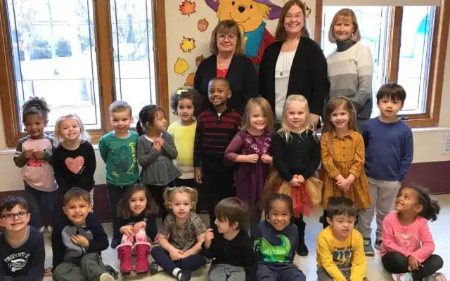 A preschool class smiles for a class photo with their teachers.