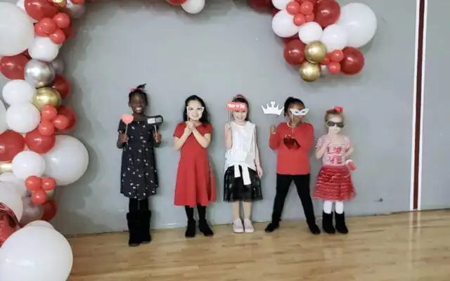 Children stand under balloons on Valentine's Day.